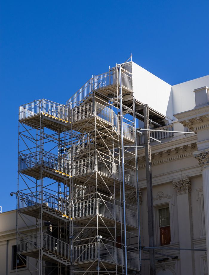 Metal scaffolding on a beautiful historical building undergoing renovation, set against a clear blue sky.